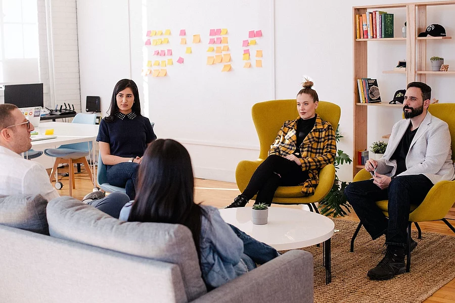 This picture shows a group of young people taking part in a meeting in a bright, modern room.